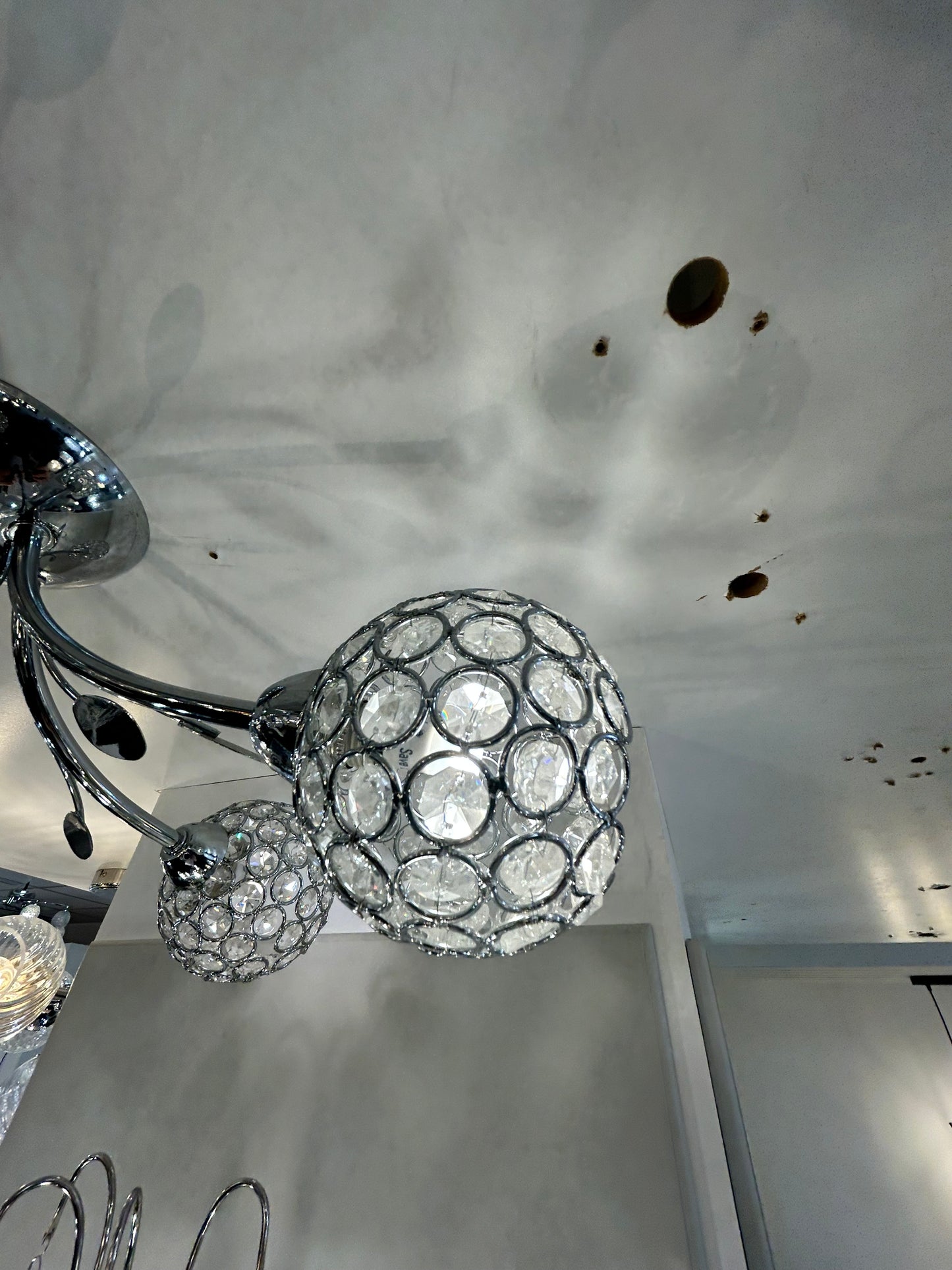 Searchlight decorative crystal ball on a metallic stand against a textured wall.