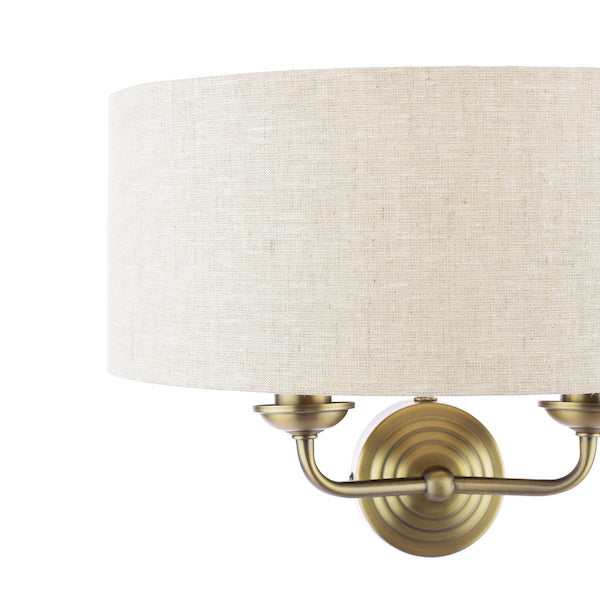Close up of natural shade on two arm antique brass wall light.