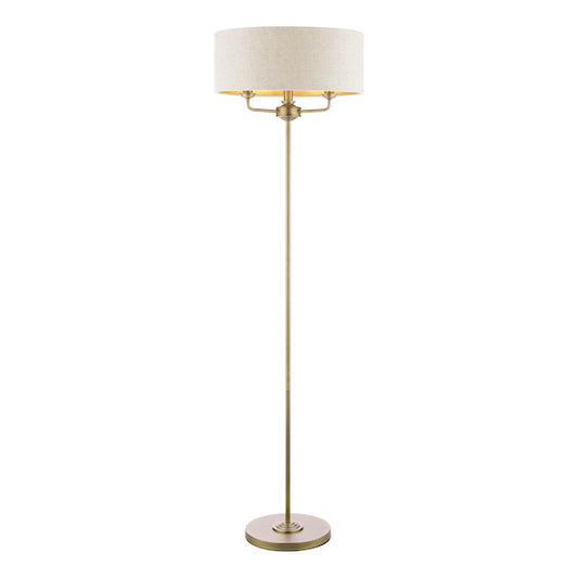 Floor lamp with a natural shade and antique brass base on a white background