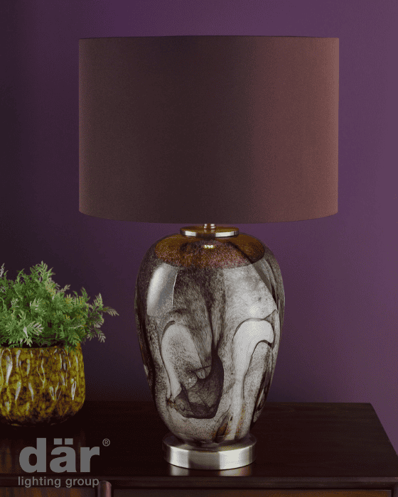 Decorative dar lighting lamp with a marbled design on a dark surface against a purple wall.