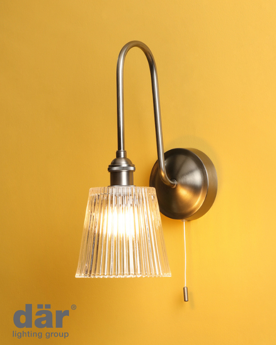 Wall-mounted light fitting with ribbed glass shade with pull cord switch against a yellow background