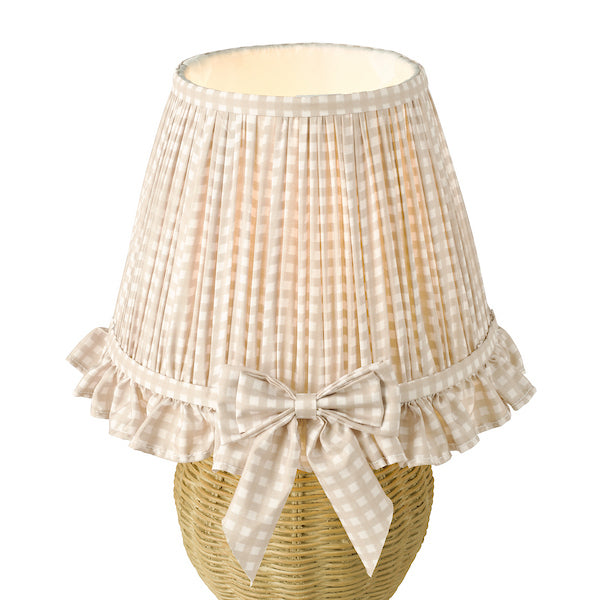 Wicker table lamp with pleated beige shade and bow on a white background