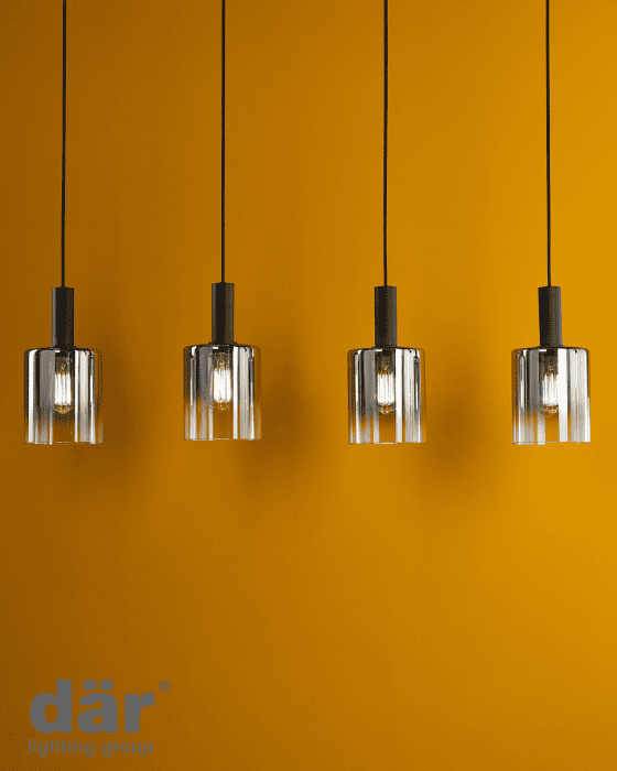 Four pendant lights hanging against an orange wall with dar lighting branding.