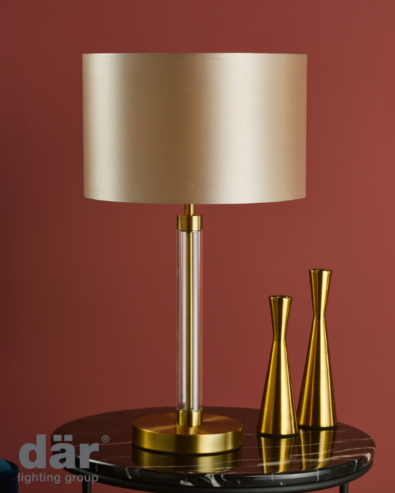 Gold dar lighting table lamp with beige shade on a round table against a red wall