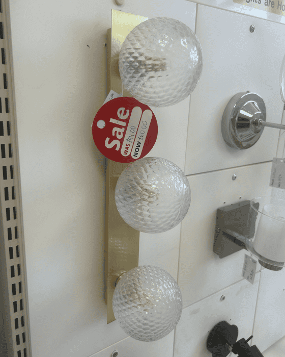 Laura Ashley decorative light fixture with crystal balls on a tiled wall, featuring a 'Sale' sign.