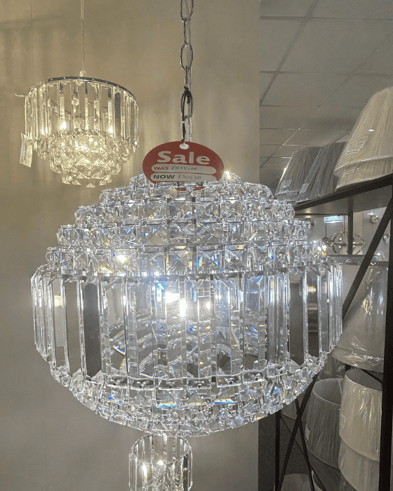 Laura Ashley crystal chandelier with a 'Sale' tag in a store setting