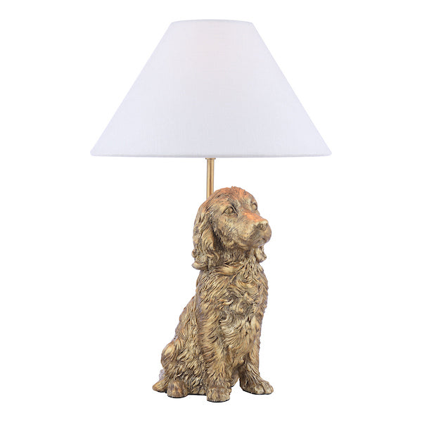 Dog-shaped antique gold table lamp with a ivory linen shade on a white background