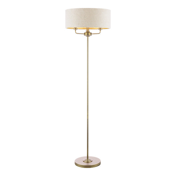 Floor lamp with a natural shade and antique brass base on a white background
