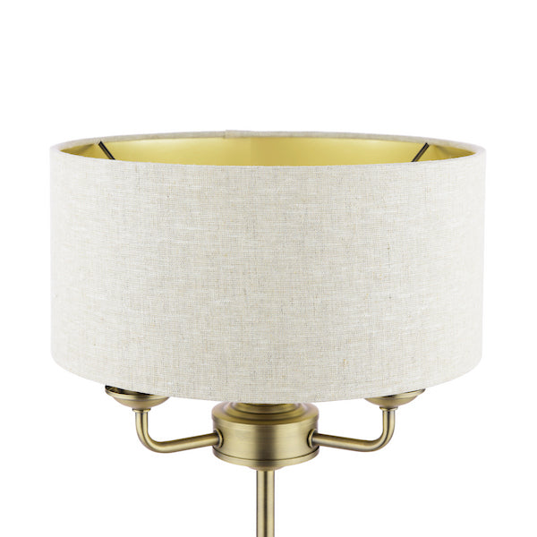 Close up of natural shade on antique brass table lamp base on white background.